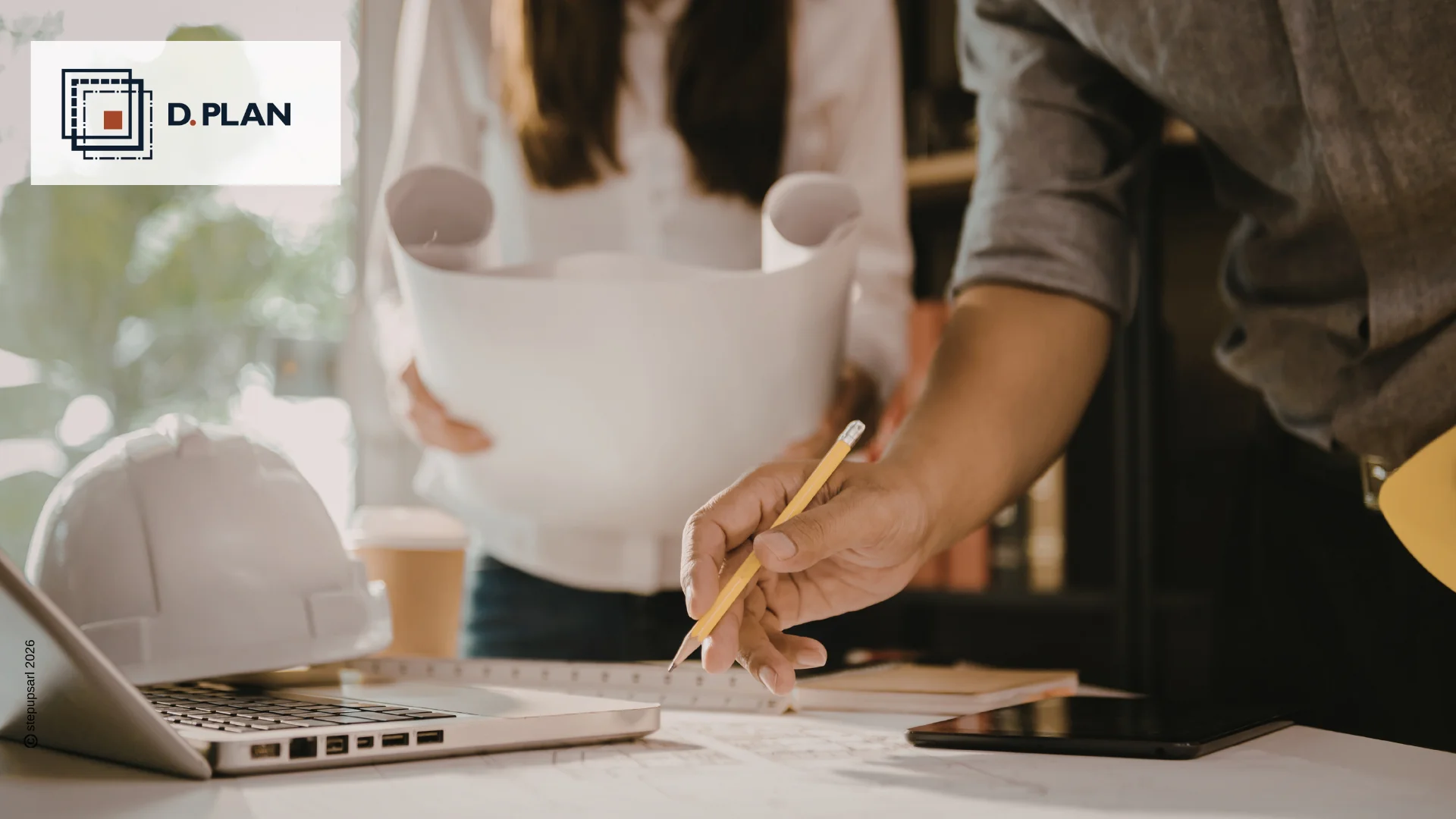 Main d'un expert utilisant un crayon pour vérifier les détails d'un plan technique sur une table de travail avec un ordinateur.